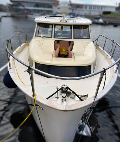 Fortøyd båt med hender ut av åpen takluke.